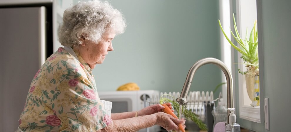 elderly woman washing vegetables at home