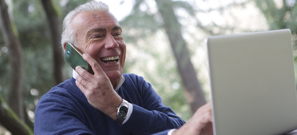 elderly man using a mobile phone and laptop